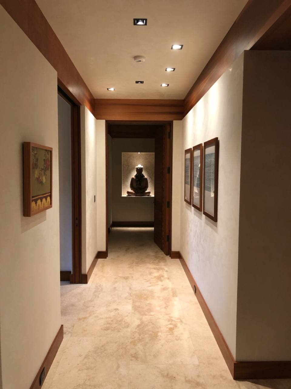 Hallway with Buddha niche and Lutron lighting scenes — travertine floors, koa trim