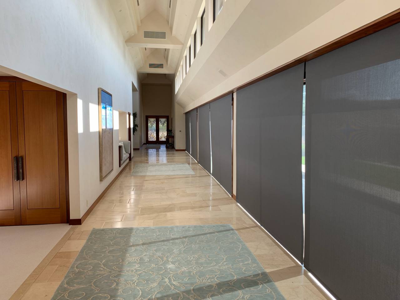 Grand hallway — vaulted beams, Lutron roller shades, polished stone, clerestory windows