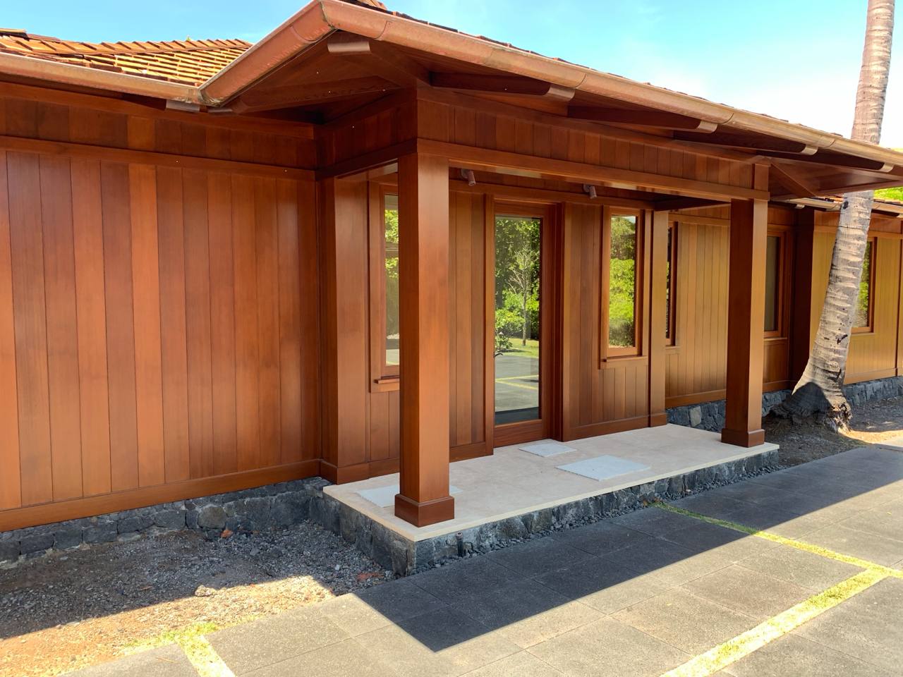 Kukio residence — koa wood siding, lava rock foundation, palm trees