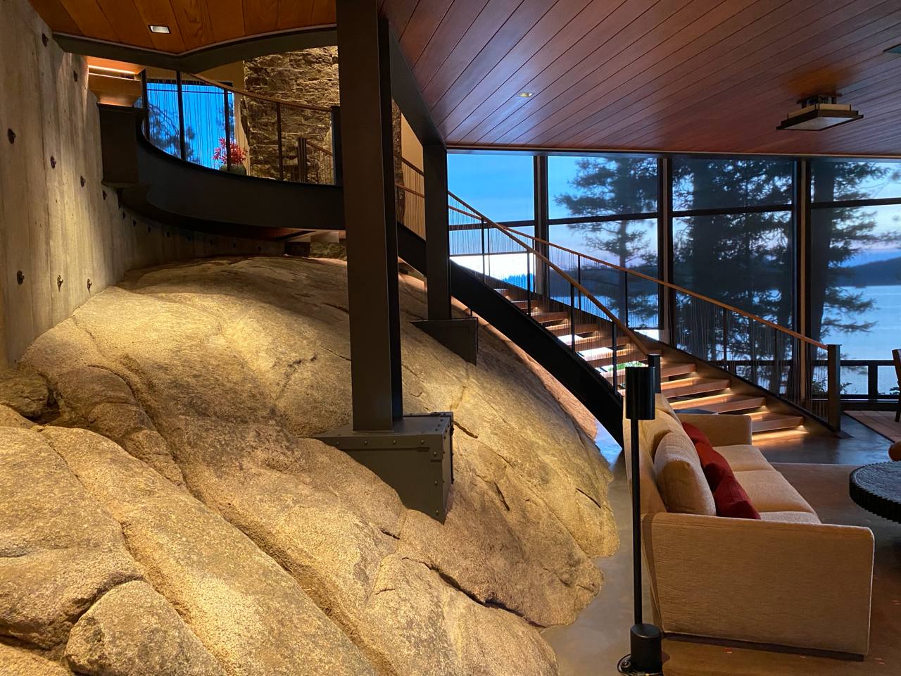 McCall Idaho — boulder staircase at twilight, lake through glass, warm wood ceiling, steel columns