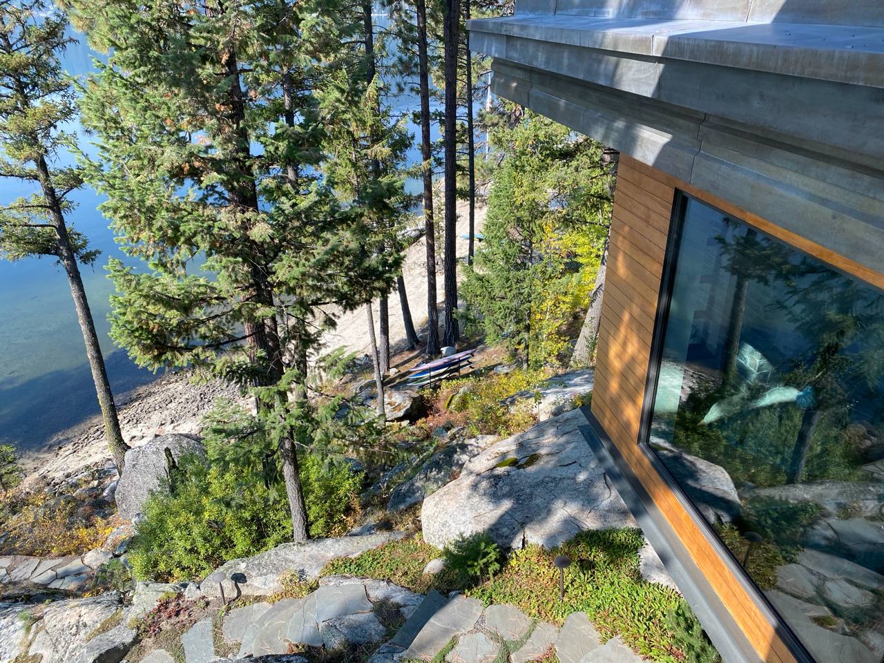 McCall Idaho — wood-clad cabin on granite hillside, floor-to-ceiling glass, lake through pines