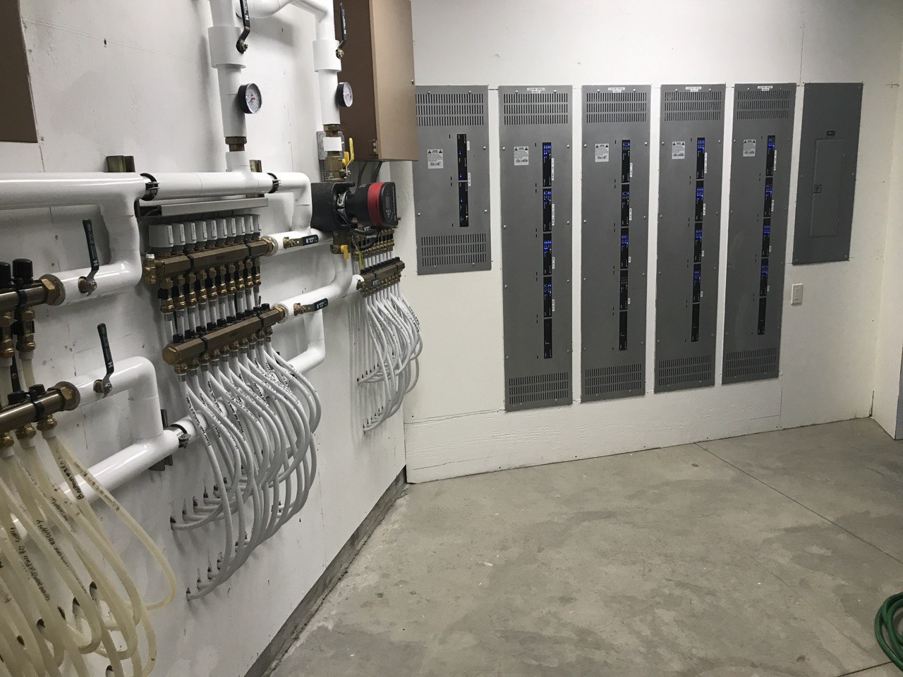 Mechanical room — radiant floor manifolds, 6 breaker panels, PEX, pumps
