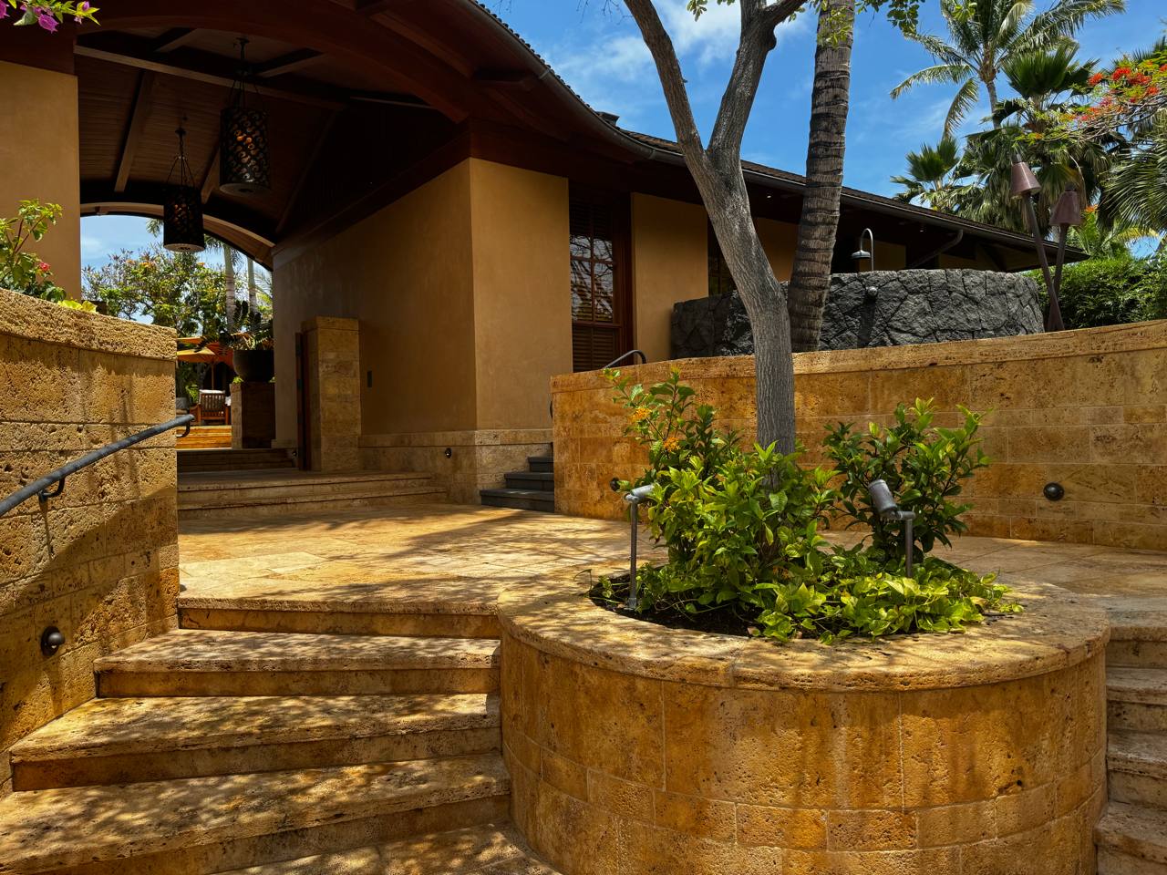 Resort entrance — travertine steps, tiki torches, bougainvillea, royal poinciana